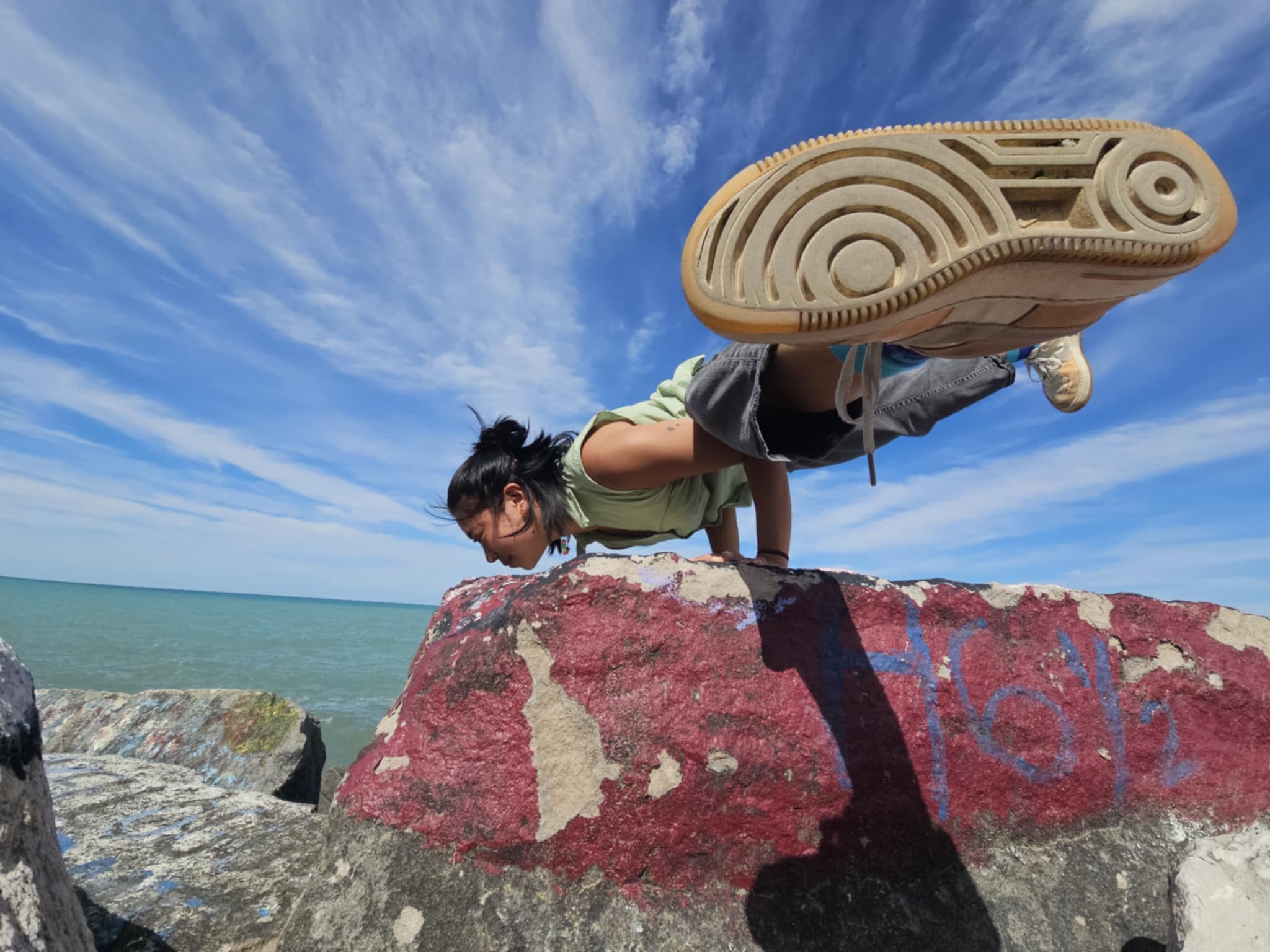 Tina doing flying crow on rock near lake